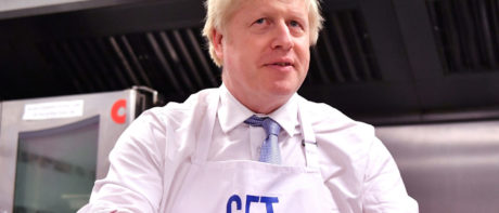 boris johnson holding a pie and wearing a get Brexit done apron