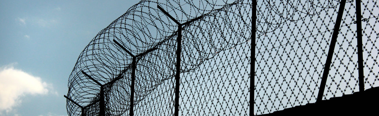 Silhouette of concertina barbed wire on a prison fence