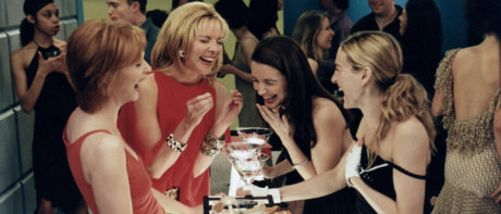The four protagonists of sex and the city stand in a cocktail bar laughing