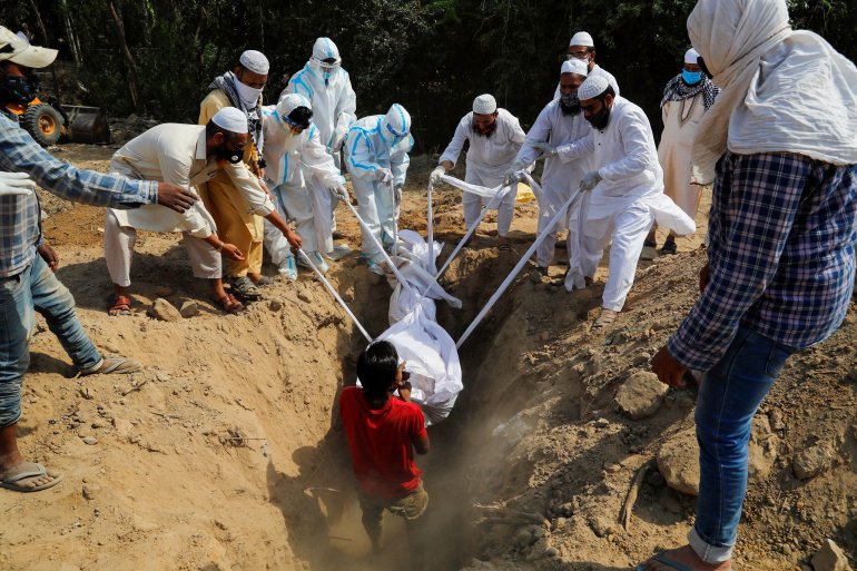 People lower the body of a man who died from Covid-19 into a grave during his funeral at a graveyard in New Delhi, April 2021. Ninian Reid/Flickr