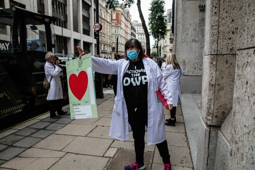 Artist and activist Dolly Sen holds out a red heart placard outside the DWP