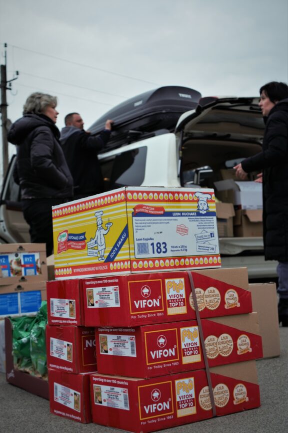 A group of people stand next to their cars and boxes of food