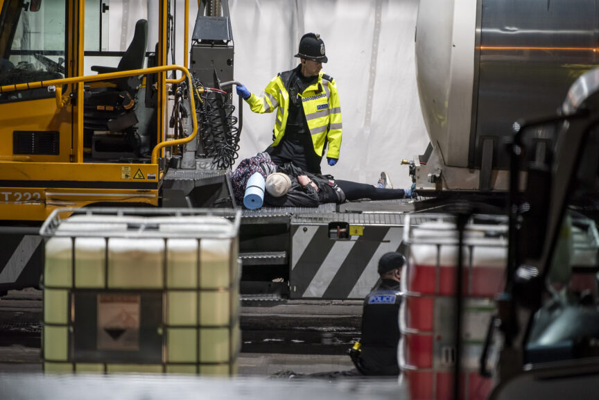 An animal rebellion protester lies on a truck in a dairy factory with a police officer looking on