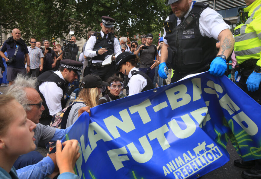 Animal Rebellion protesters are arrested as they sit in the street with a banner that reads 'plant-based future'