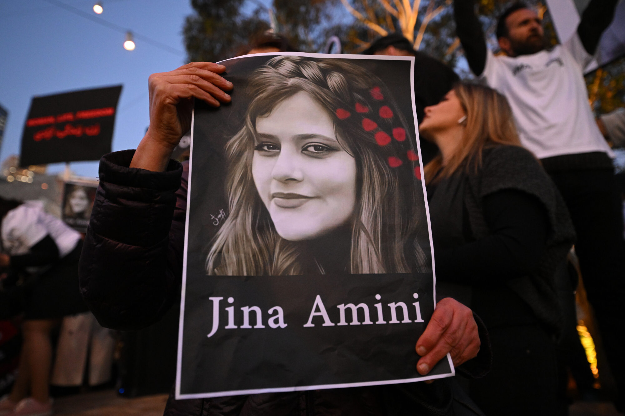 A protester holds a placard picturing Jina Amini during a demonstration following the death of Mahsa Amini in Iran, at Federation Square in Melbourne, Thursday, September 29, 2022. Protests have continued to rage in Iran over the death in custody of Mahsa Amini, with demonstrators calling for the end of clerical rule. (AAP Image/James Ross) NO ARCHIVINGNo Use Australia. No Use New Zealand.