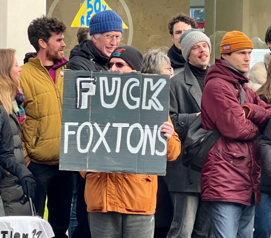 A man holds a banner reading 'fuck Foxtons'