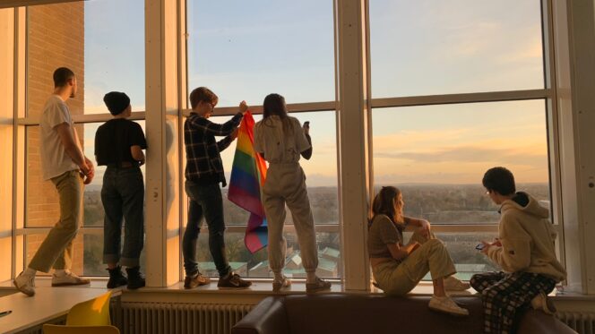 a group of people stand in front of a window at sunset