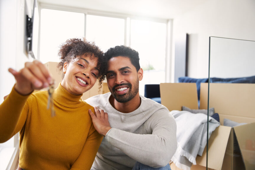 A tacky stock photo of a young couple holding keys to their first home.