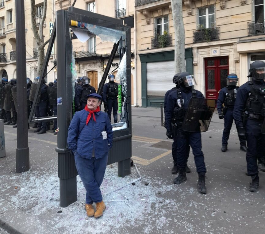 A man stands next to some riot police on 7 March. Olly Haynes