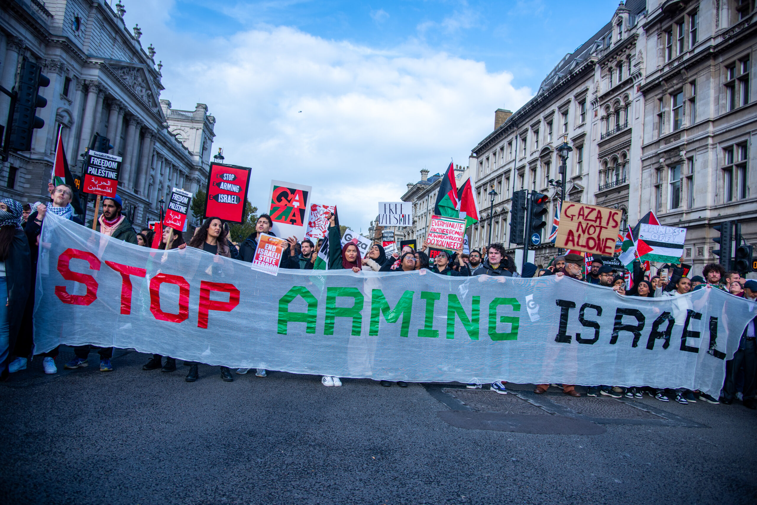 Protestors march with a large 'stop arming Israel' banner at a national march for Palestine in London