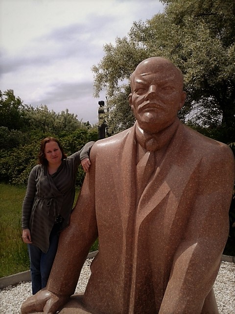 a woman stands beside a large statue of lenin