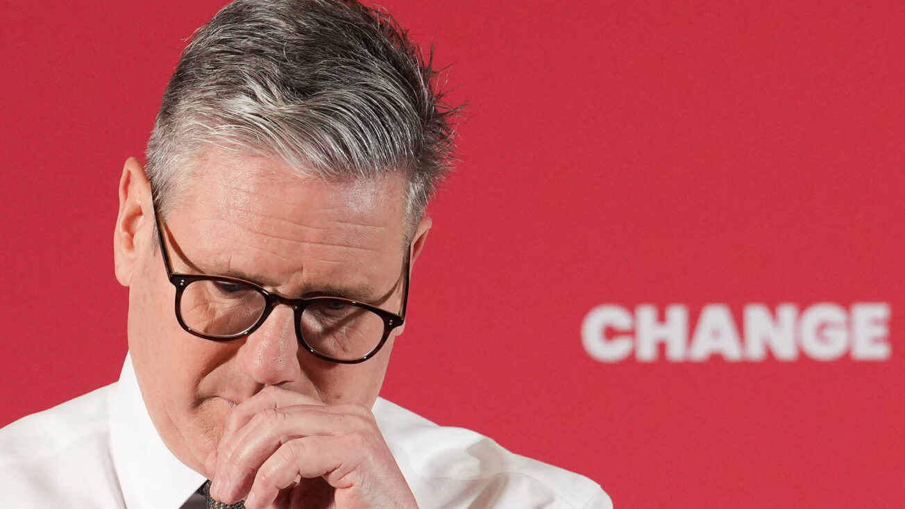 Keir Starmer looks sad behind a red background that says 'change'