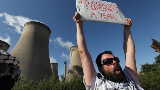 A demonstrator outside Drax power station holds a sign about government subsidies. ZUMA Press, Inc. / Alamy Stock Photo