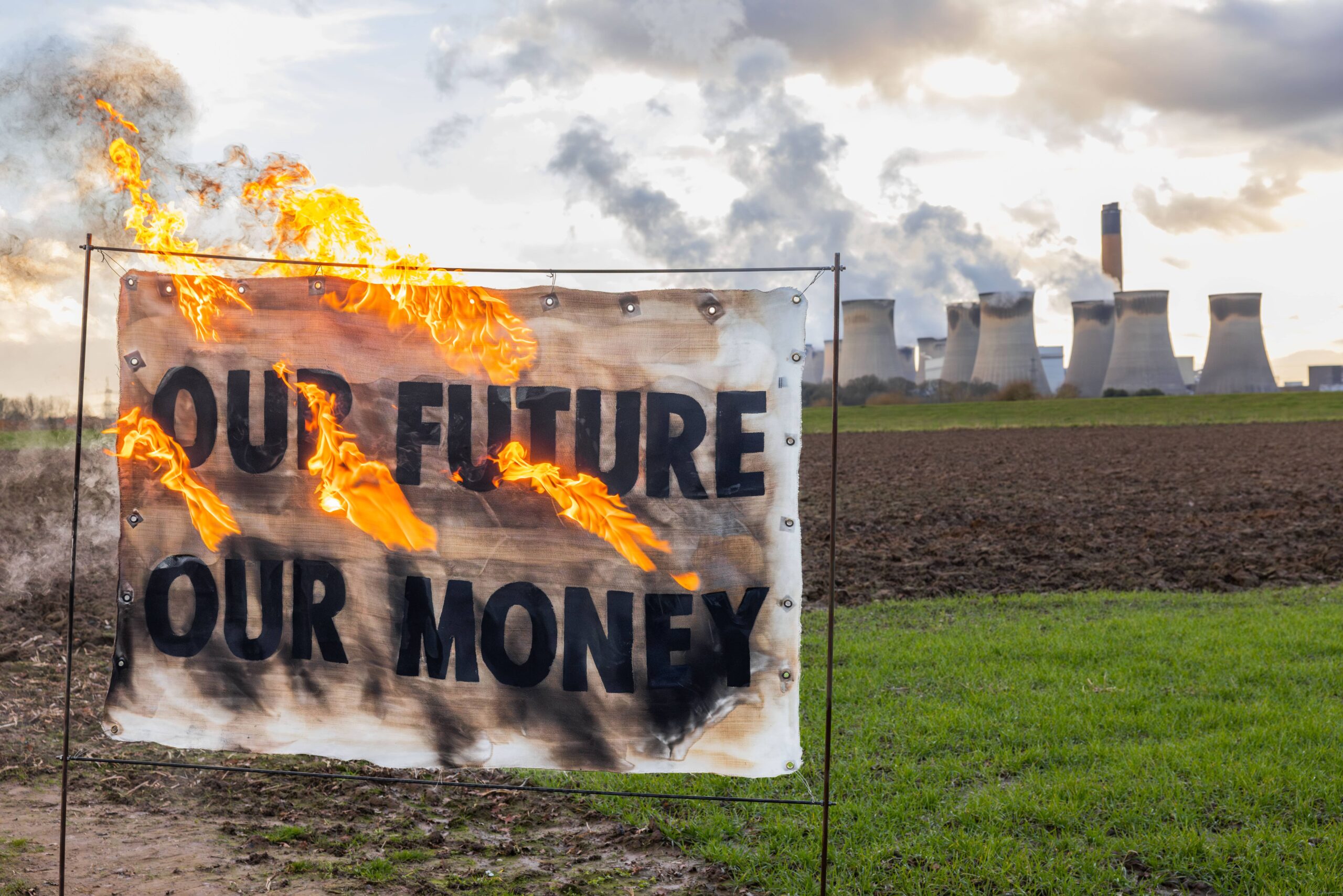 A banner is burned in protest outside Drax power station in North Yorkshire. Image: Axe Drax
