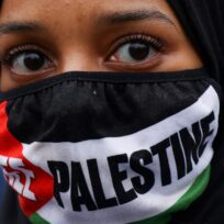 A demonstrator with a face covering in the colours of the Palestinian flag attends a protest in solidarity with Palestinians in Gaza, April 2024. Hollie Adams/Reuters