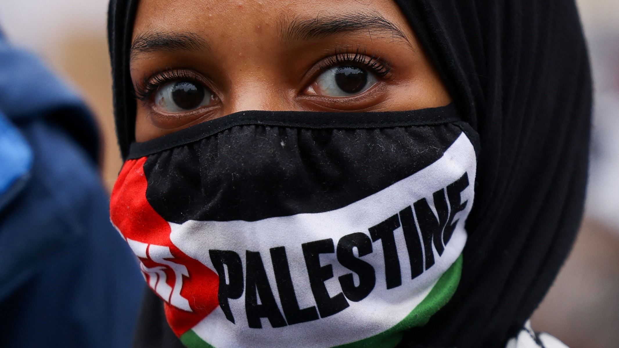 A demonstrator with a face covering in the colours of the Palestinian flag attends a protest in solidarity with Palestinians in Gaza, April 2024. Hollie Adams/Reuters