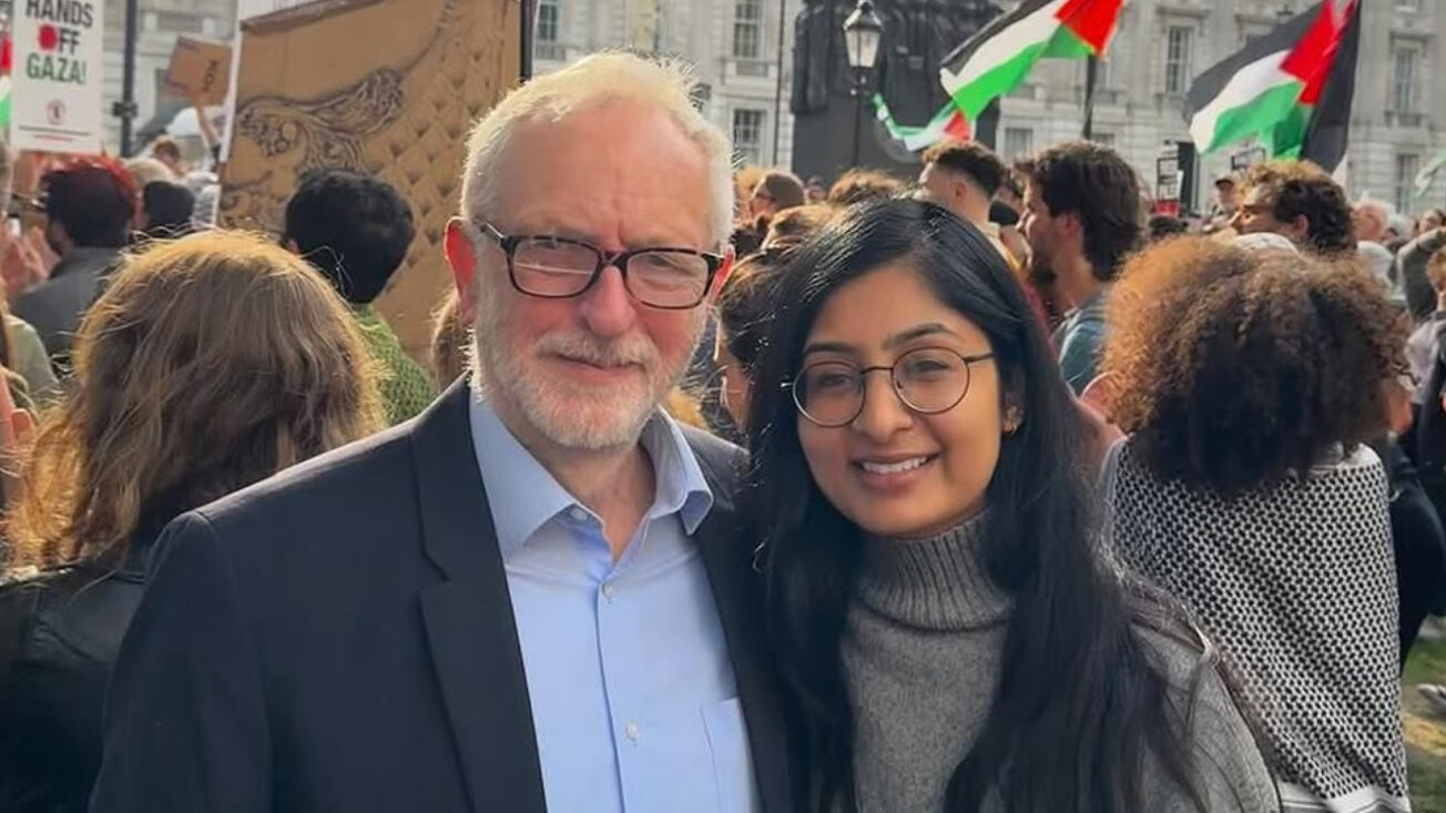 A man with white hair and glasses stands beside a woman with long brown hair and glasses