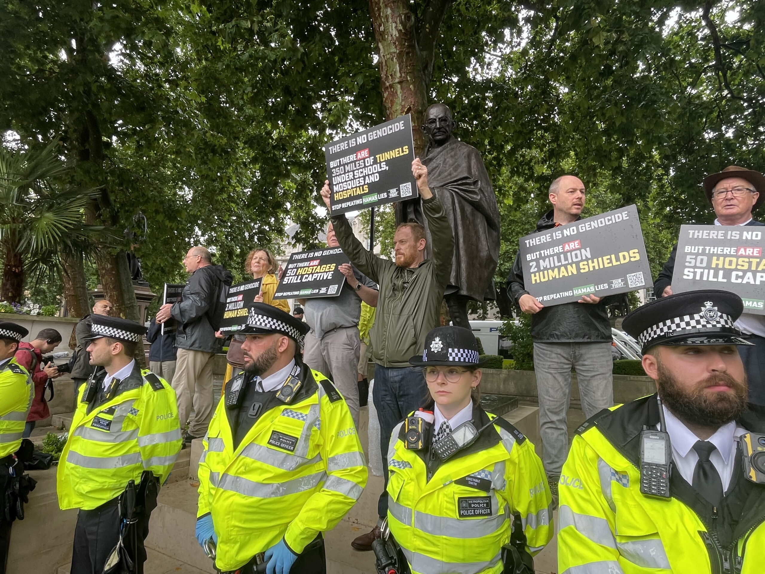 Counter protesters hold up signs that claim there are '2 million human shields in Gaza' and are protected by the police.