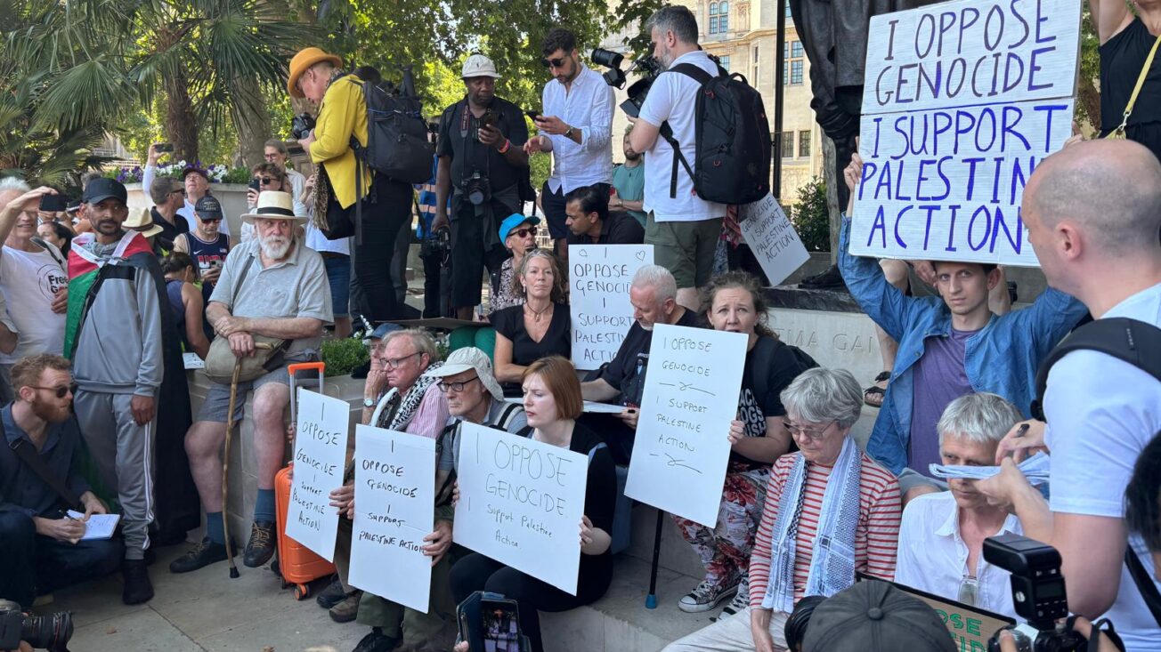 Activists sit in Parliament Square with signs