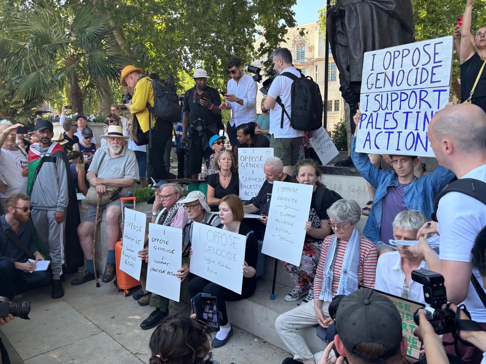 Activists sit in Parliament Square with signs