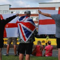 Anti-immigration demonstrators display Union Jack and England flags as they gather outside a hotel in Altrincham, 8 August 2025. Phil Noble/Reuters