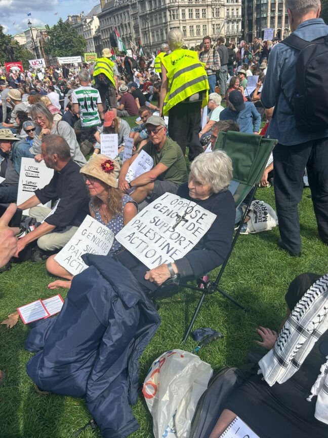 Reverend Sue Parfitt, an 83-year-old priest, holding a sign in London's Parliament Square