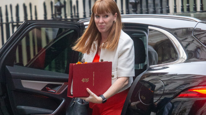 A woman with long red hair steps out of a cab carrying a red briefcase