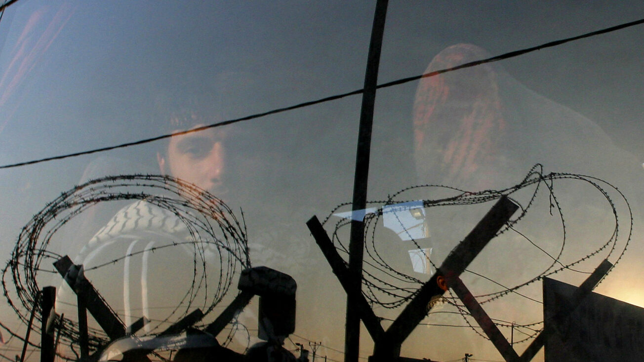 Palestinian prisoner stares out of a bus window as he and other prisoners leave Ketziot military prison in southern Israel, in June 2005. REUTERS/Ronen Zvulun