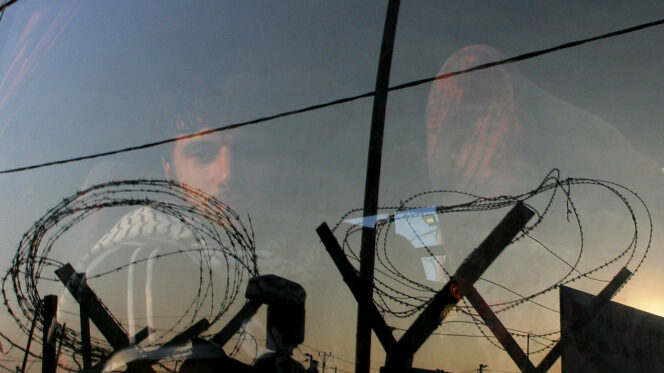 Palestinian prisoner stares out of a bus window as he and other prisoners leave Ketziot military prison in southern Israel, in June 2005. REUTERS/Ronen Zvulun