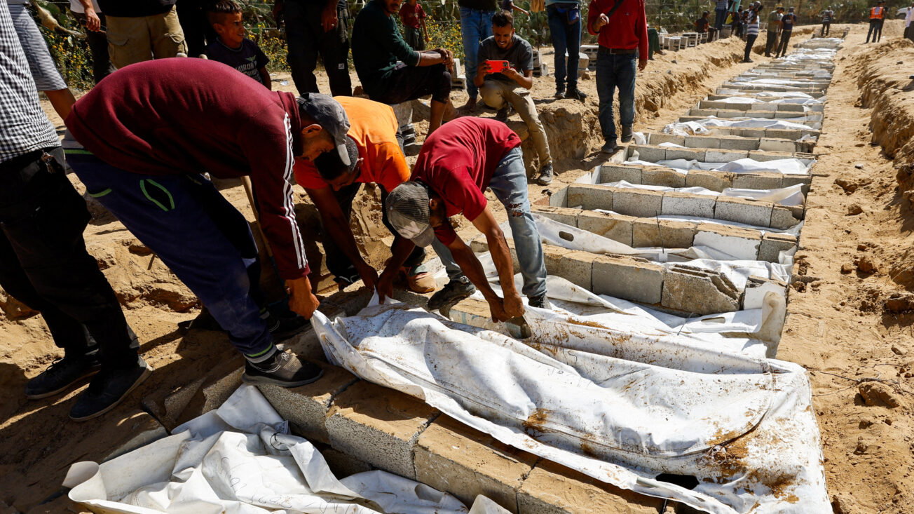People bury the unidentified bodies of Palestinians who had been held in Israel during the war, after they were handed over by Israel in Deir Al-Balah, central Gaza, on 22 October 2025.