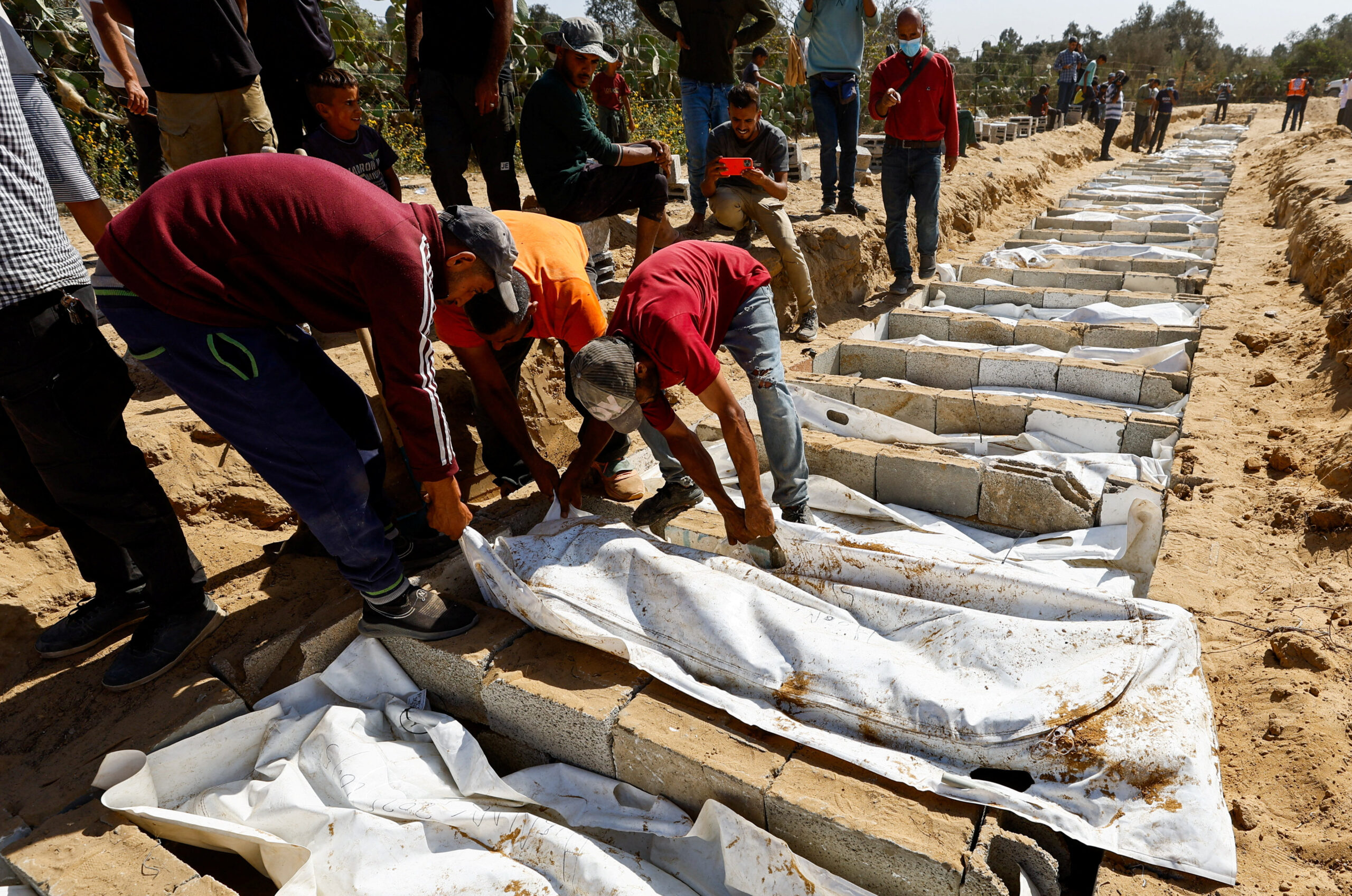People bury the unidentified bodies of Palestinians who had been held in Israel during the war, after they were handed over by Israel in Deir Al-Balah, central Gaza, on 22 October 2025.