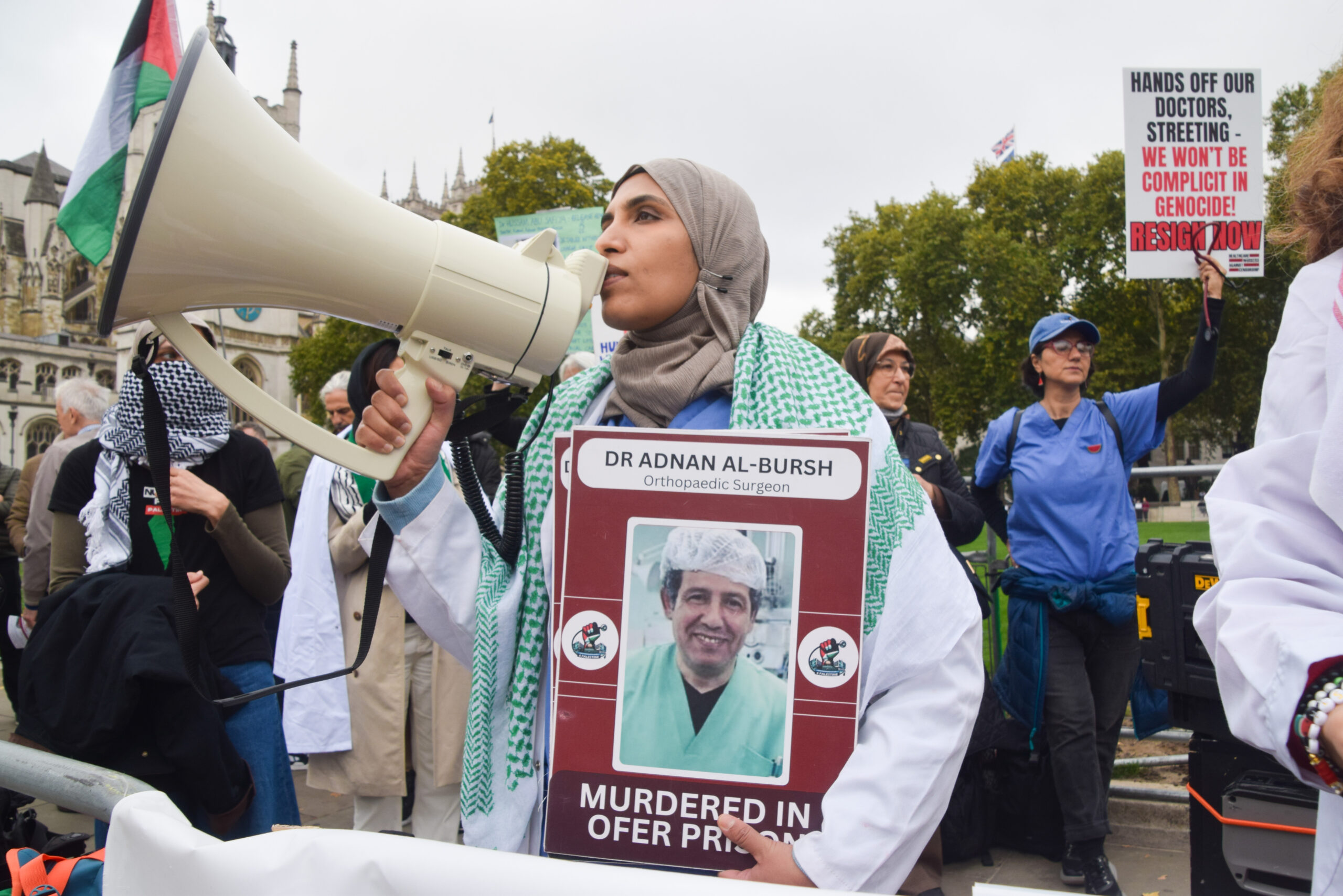 CAPTION: A protester holds a picture of Palestinian doctor Adnan Al-Bursh, who died in an Israeli prison, and chants slogans through a megaphone during the demonstration in Parliament Square. SOPA Images / Reuters