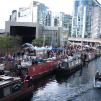 a canal with houseboats with buildings besides the canal
