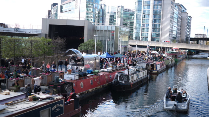 a canal with houseboats with buildings besides the canal