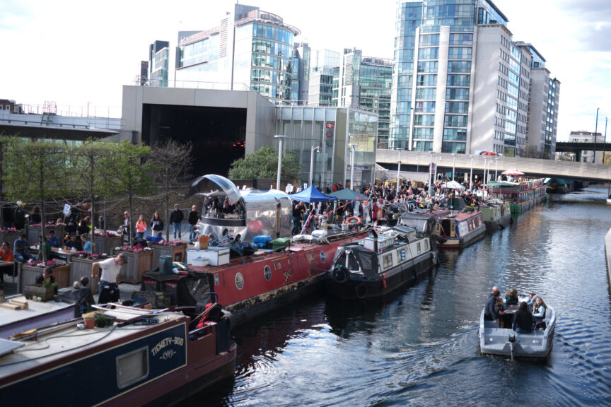 a canal with houseboats with buildings besides the canal