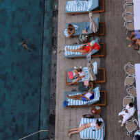 People on sun loungers beside a pool in Dubai.