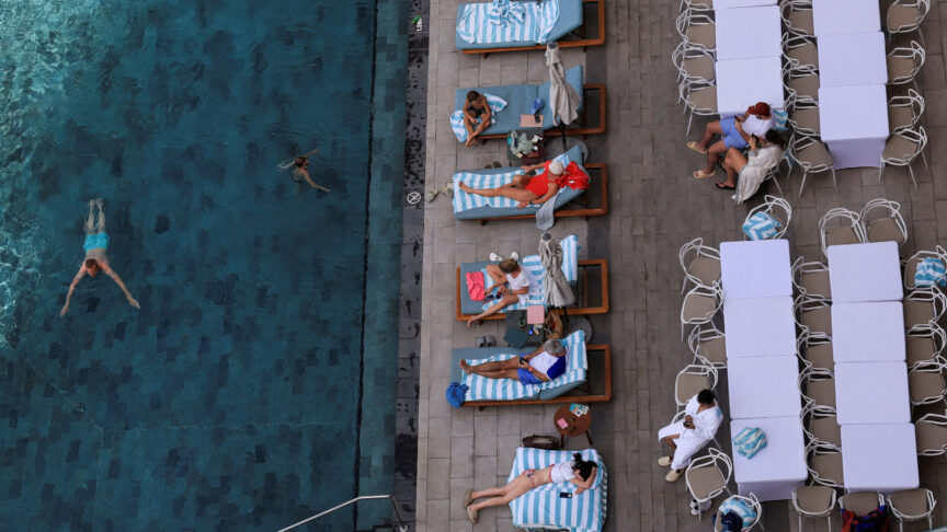 People on sun loungers beside a pool in Dubai.