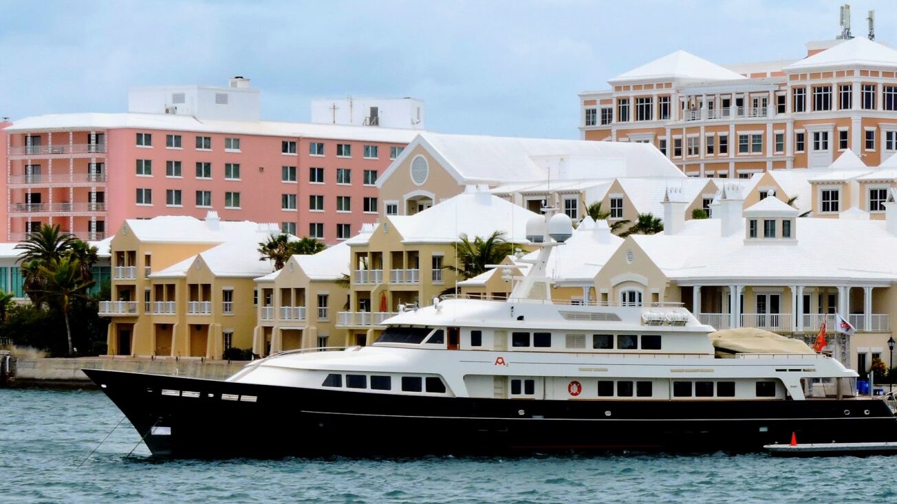A large boat in a port surrounded by pink and yellow buildings