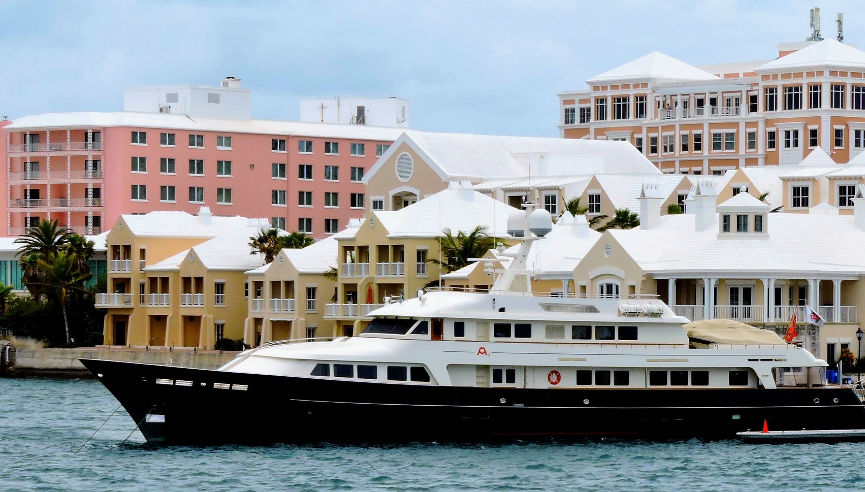 A large boat in a port surrounded by pink and yellow buildings