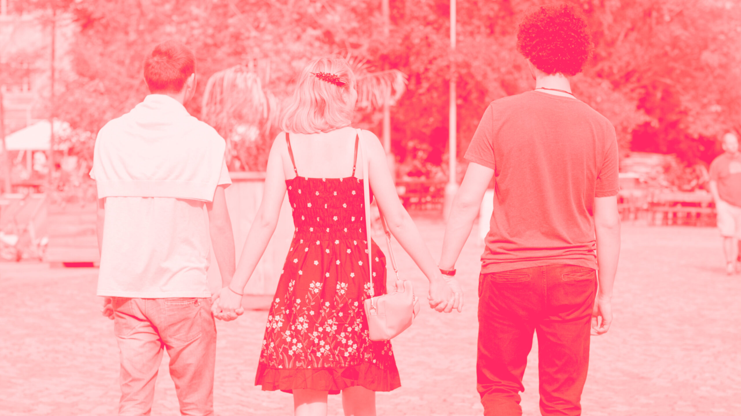 A woman holds the hands of two men in a town square