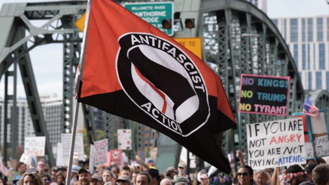 An antifascist action flag is displayed as protesters take part in the nationwide No Kings protest against the authoritarian policies of President Trump in Portland, Oregon on 18 October 2025. (Alex Milan Tracy/Sipa USA)