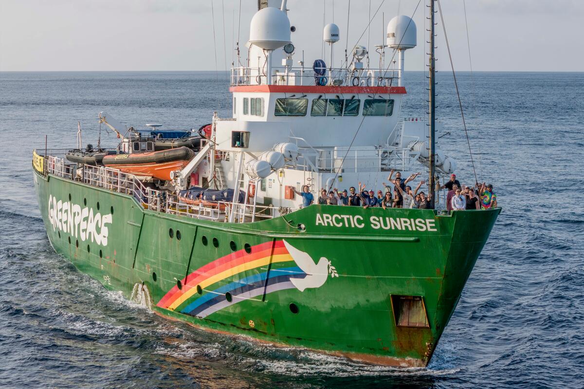 A large boat called Arctic Sunrise sails with lots of triumphant people on board