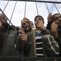Palestinians stand behind the bars of a symbolic cage