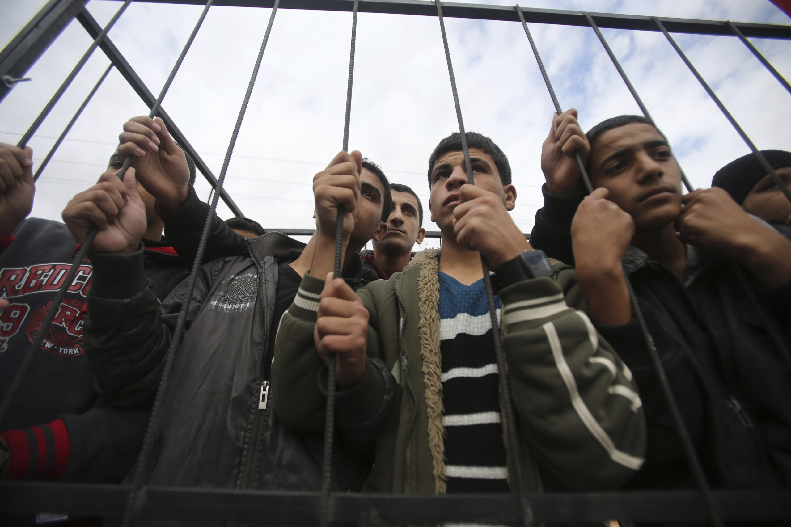 Palestinians stand behind the bars of a symbolic cage