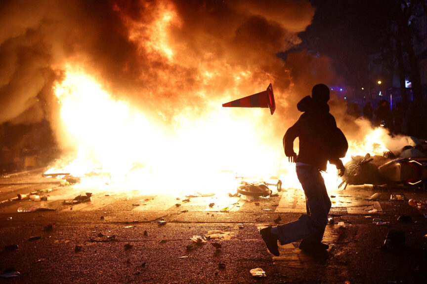 A man throws a plastic traffic cone through a burning barricade in Paris as part of nationwide protests called by the 'Yellow Vests' movement, joined by French high school and university students, teachers, trade unions and parents demanding better school conditions. Photo: REUTERS/Abdul Saboor